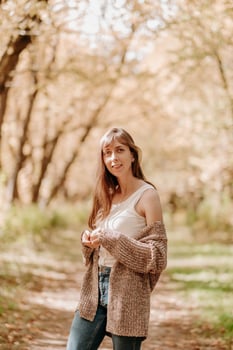 portrait of a girl with brown hair, in a cardigan, on a walk in the forest. photo