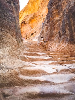 Caucasian tourist girl stand on staircase to A'dir monastery on mountain in Petra lost city historical landmark photo