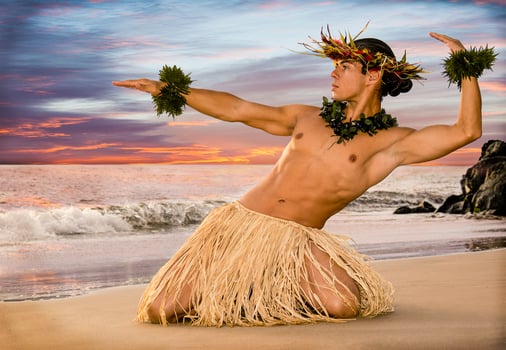 Handsome Male Hula Dancer on the beach at sunset in traditional costume grass skirt. photo