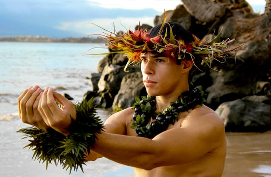 Male Hula Dancer poses on the beach with a giving gesture of the hula dance.. photo