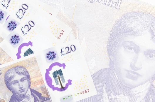 20 British pounds bills lies in stack on background of big semi-transparent banknote. Abstract business background photo