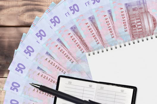 50 Ukrainian hryvnias bills fan and notepad with contact book and black pen. Concept of financial planning and business strategy photo