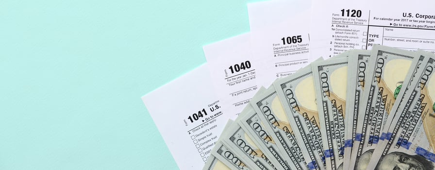 Tax forms lies near hundred dollar bills and blue pen on a light blue background. Income tax return photo