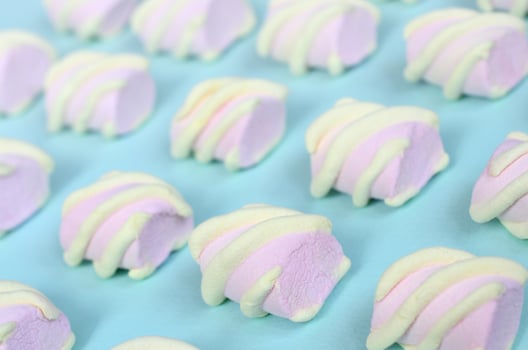 Colorful marshmallow laid out on blue paper background. pastel creative textured pattern. Perspective macro shot photo