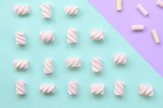 Colorful marshmallow laid out on violet and blue paper background. pastel creative textured pattern. minimal photo