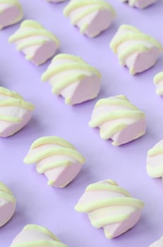 Colorful marshmallow laid out on violet paper background. pastel creative textured pattern. Perspective macro shot photo