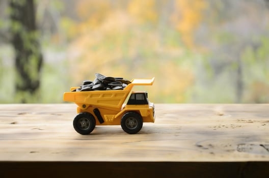 A small yellow toy truck is loaded with sunflower seeds. A car on a wooden surface against a background of autumn forest. Extraction and transportation of sunflower seeds photo