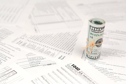 1040 Individual income tax return form with roll of american dollar banknotes photo