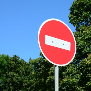 A circular red sign with a white bar indicating NO ENTRY on a grey metal post photo
