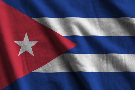 Cuba flag with big folds waving close up under the studio light indoors. The official symbols and colors in banner photo