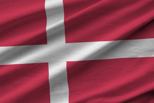 Denmark flag with big folds waving close up under the studio light indoors. The official symbols and colors in banner photo