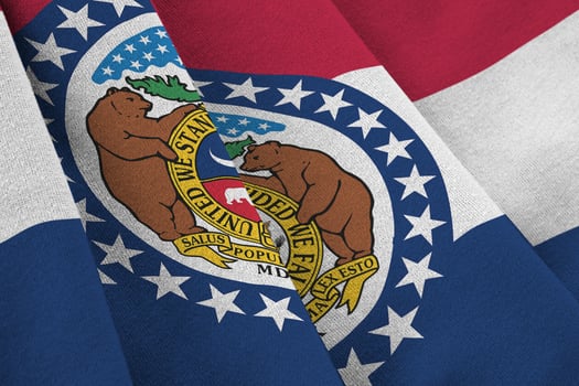 Missouri US state flag with big folds waving close up under the studio light indoors. The official symbols and colors in banner photo