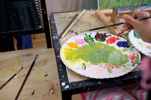 Close-up shot, acrylic colors palette, mixing and painting a picture by artist's hand, vivid multicolor in canvas with easel, colorful creativity with talent skills, artistic imagination design. photo