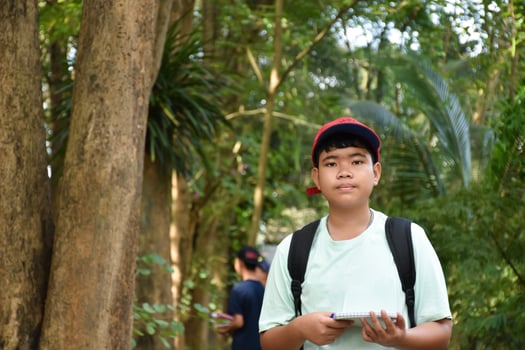 Three asian boys're reading birds details and going to use binoculars to watch birds on the trees during summer camp, idea for learning creatures and wildlife animals outside the classroom. photo