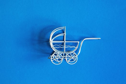 vintage toy baby stroller on blue background. toy carriage photo