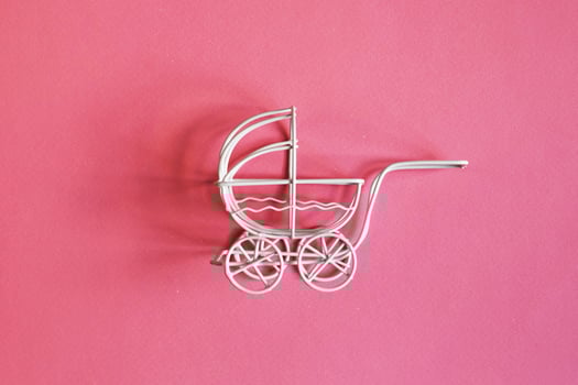 vintage toy baby stroller on pink background. toy carriage photo