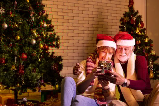 Senior caucasian couple celebrating Christmas together in happiness and excitement at home with red Santa hat and christmas tree photo