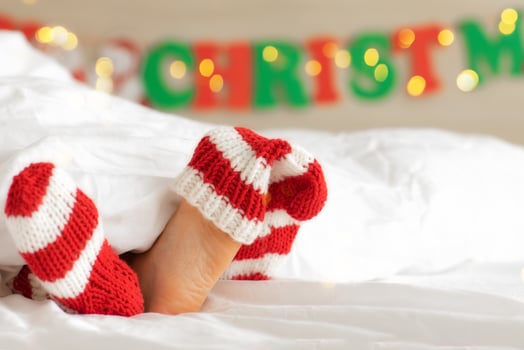 Children bare feet close up and wool knitted red white socks.Festive mood.Christmas concept, holiday.Happy New Year.Child girl under white fluffy blanket photo