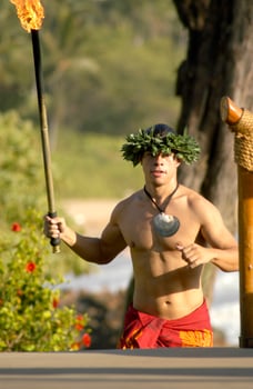 A male hula dancer runs with a tiki torch to light the stages lights for the performance. photo