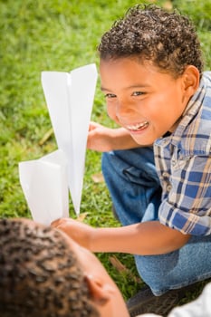 Mixed Race Father and Son Playing with Paper Airplanes photo