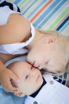Little Sister Laying Next to Her Baby Brother on Blanket photo
