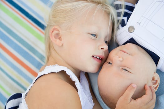 Little Sister Laying Next to Her Baby Brother on Blanket photo