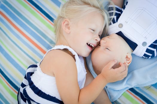 Little Sister Laying Next to Her Baby Brother on Blanket photo