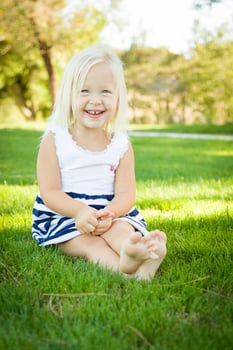 Cute Little Girl Sitting and Laughing in the Grass photo