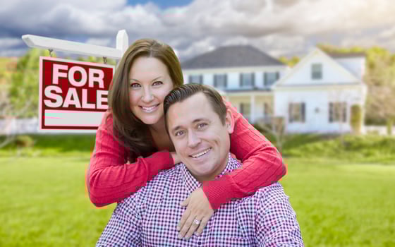 Happy Couple In Front of For Sale Sign and House photo