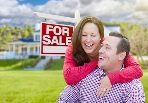 Happy Couple In Front of For Sale Sign and House photo