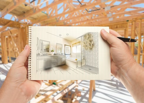 Hands Holding Pen and Pad of Paper with Bathroom Design Inside House Construction Framing. photo