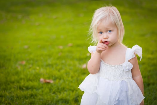 Adorable Little Girl Wearing White Dress In A Grass Field photo