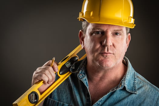 Serious Contractor in Hard Hat Holding Level and Pencil With Dramatic Lighting. photo