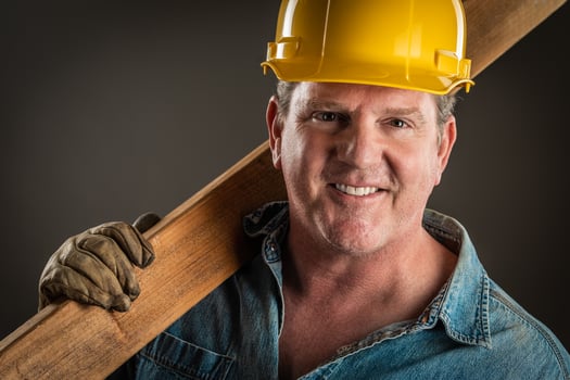 Smiling Contractor in Hard Hat Holding Plank of Wood With Dramatic Lighting. photo