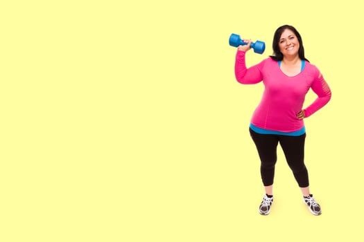 Middle Aged Hispanic Woman In Workout Clothes Holding Dumbbell Against A Bright Yellow Background photo
