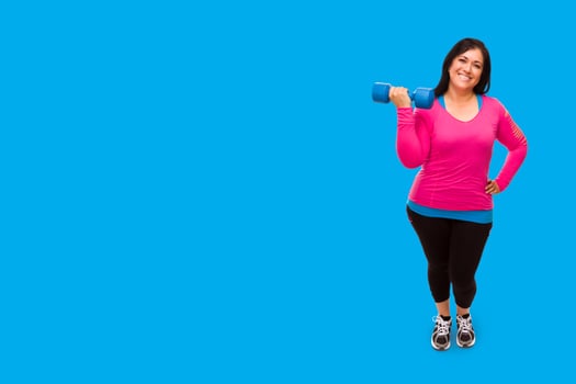 Middle Aged Hispanic Woman In Workout Clothes Holding Dumbbell Against A Bright Cyan Blue Background photo