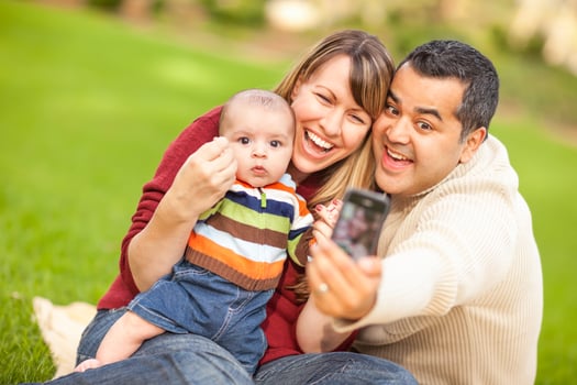 Happy Mixed Race Parents and Baby Boy Taking Self Portraits at the Park photo