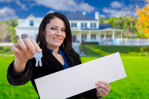 Woman Holding Blank Sign and Keys In Front of House photo
