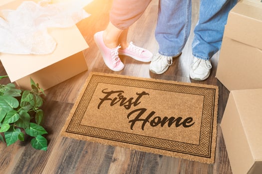 Man and Woman Unpacking Near First Home Welcome Mat, Moving Boxes and Plant photo