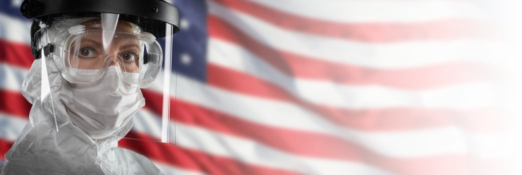 Doctor or Nurse Wearing Medical Personal Protective Equipment Against The American Flag Banner photo