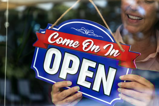 Happy Female Store Owner Turning Open Sign in Window photo