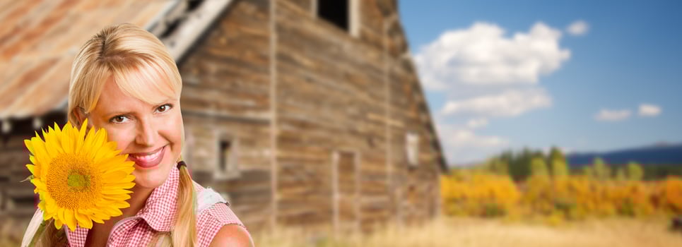 Beautiful Caucasian Young Woman Holding Sunflower In Front of Rustic Barn In The Country. photo