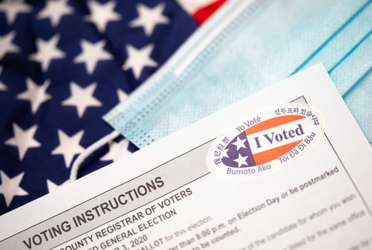 Voting Instructions and I Voted Sticker On Medical Face Mask Laying on American Flag photo