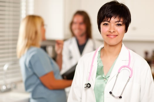 Pretty Doctor Smiles at Camera as Colleagues Talk photo