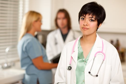 Pretty Latino Doctor Smiles at Camera as Colleagues Talk photo