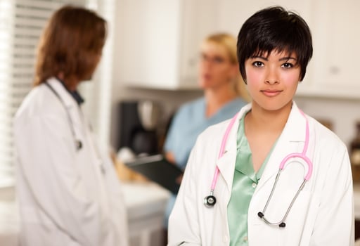 Pretty Latino Doctor Smiles at Camera as Colleagues Talk photo