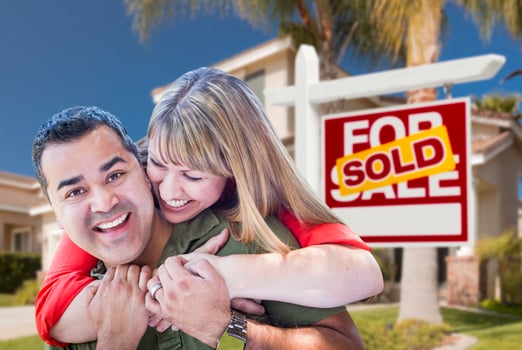 Couple in Front of Sold Real Estate Sign and House photo