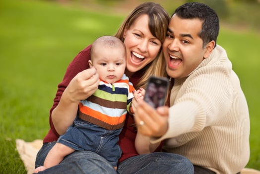 Happy Mixed Race Parents and Baby Boy Taking Self Portraits photo
