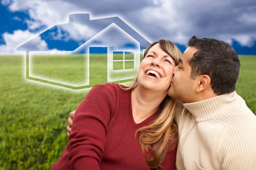 Happy Couple Sitting in Grass Field with Ghosted House Behind photo