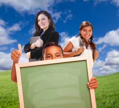 Young Students with Blank Chalk Board, Teacher Behind on Grass photo